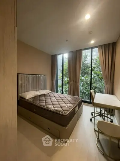 Cozy bedroom with large window and study area, perfect for relaxation and productivity.