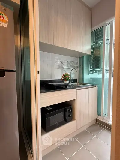 Modern compact kitchen with sleek cabinetry and built-in microwave