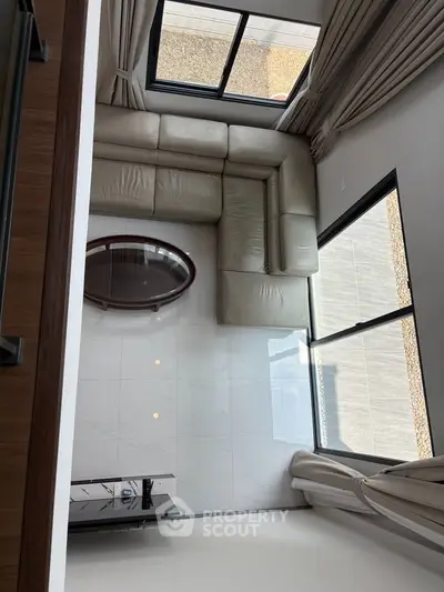 Spacious modern living room with large windows and elegant sectional sofa.