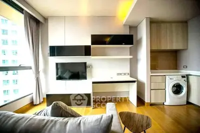 Modern living room with sleek furniture and in-unit washing machine, featuring large windows and wooden flooring.