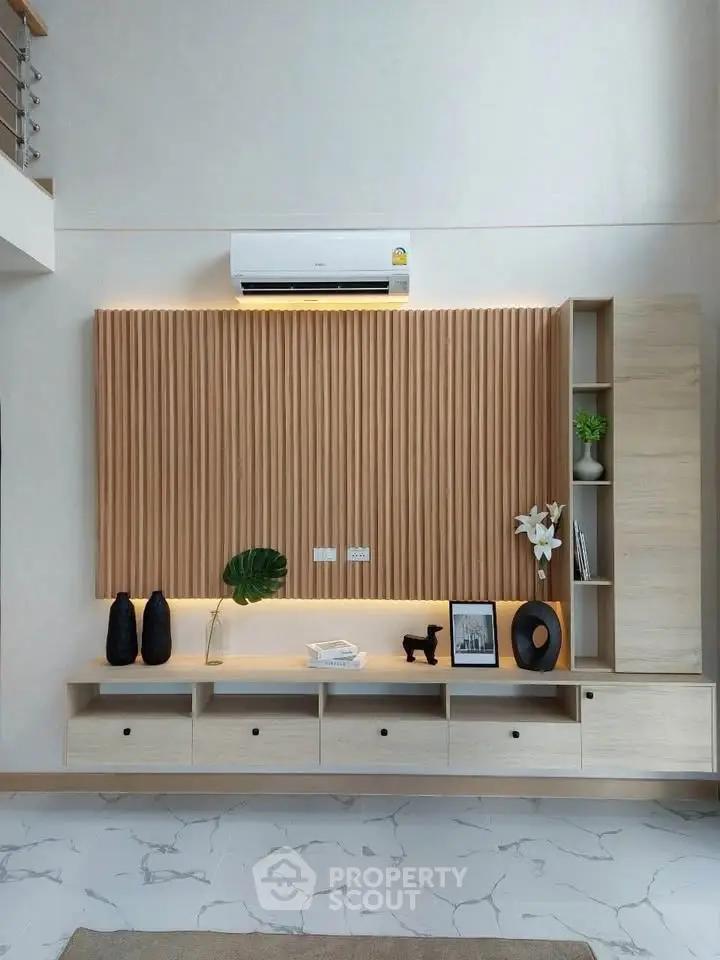 Modern living room with stylish wooden paneling and sleek storage solutions.