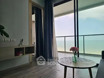 Stunning beachfront living room with floor-to-ceiling windows and ocean view balcony.