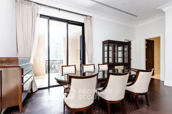 Elegant dining room with large glass doors leading to a balcony, featuring stylish furniture and natural light.
