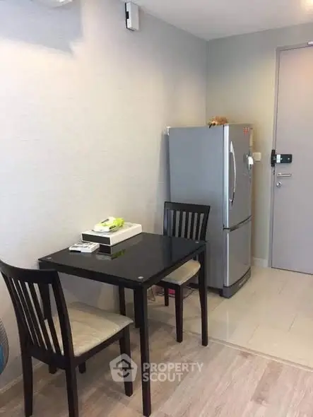 Cozy dining area with modern fridge and sleek black table in compact apartment.