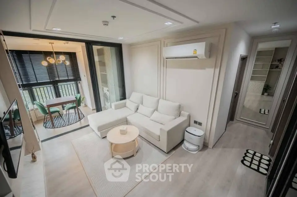Modern living room with sleek design and open balcony view, featuring a cozy white sofa and stylish decor.