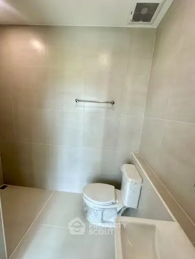 Modern bathroom with sleek tiles and compact design, featuring a toilet and sink.