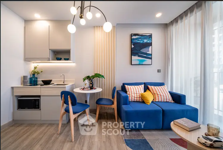 Modern living room with stylish furniture and open kitchen layout, featuring a cozy blue sofa and chic dining area.