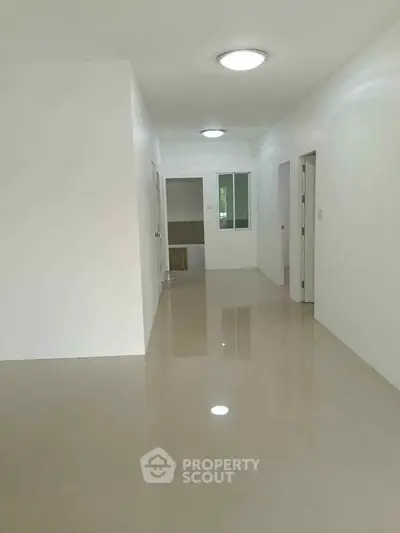 Spacious hallway with glossy tiled flooring and modern lighting in a minimalist apartment.