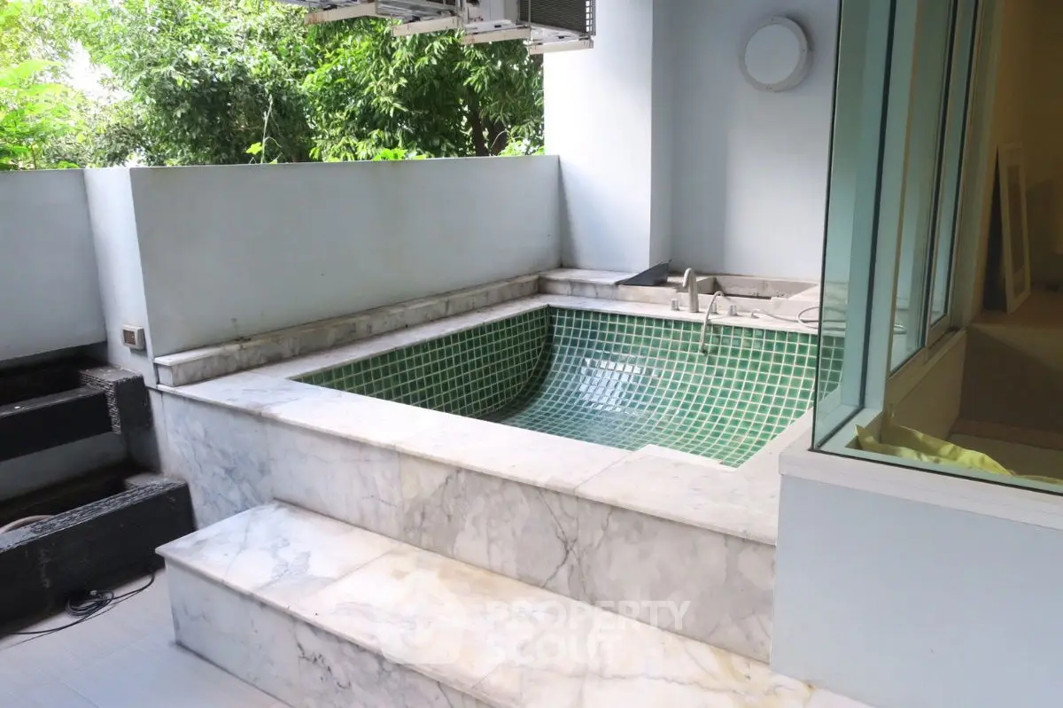 Luxurious private jacuzzi on marble terrace with lush greenery view
