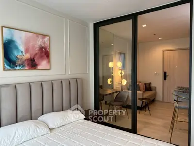 Modern bedroom with elegant decor and glass partition leading to stylish living area.