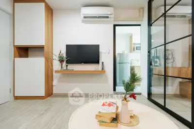 Modern living room with sleek design, featuring a wall-mounted TV, air conditioning, and stylish decor.
