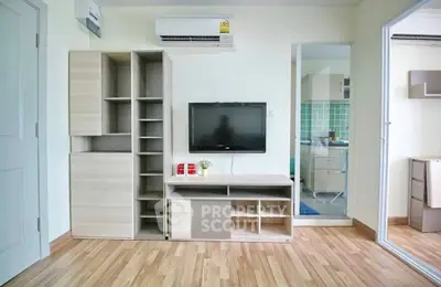 Modern living room with sleek wooden flooring and stylish TV unit, adjacent to a kitchen with green backsplash.