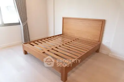 Spacious bedroom with wooden bed frame and natural light