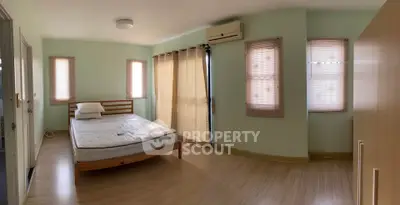 Spacious bedroom with natural light and wooden flooring