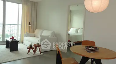 Modern living room with cozy seating and dining area, featuring a view into a stylish bedroom.