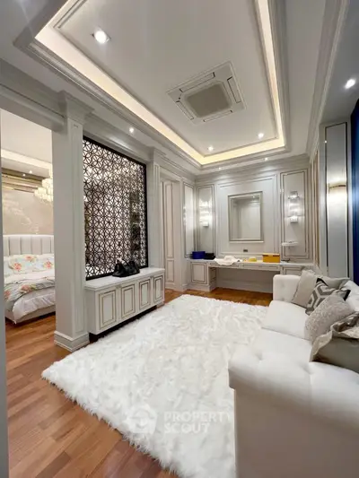 Luxurious living room with elegant decor and plush white rug, adjacent to a stylish bedroom.