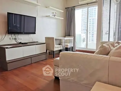 Modern living room with sleek TV, cozy sofa, and balcony view in a stylish apartment.