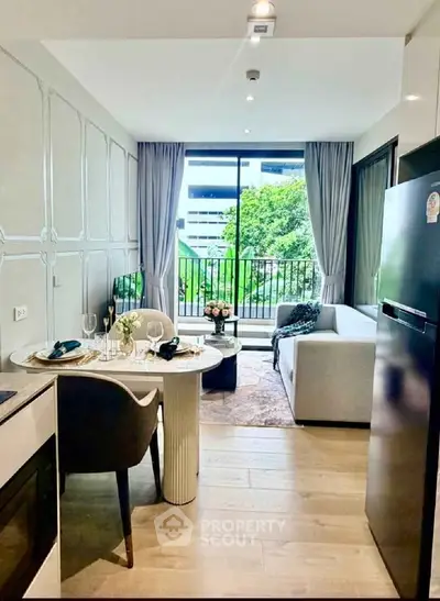 Modern living room with open kitchen and balcony view, featuring elegant decor and natural light.