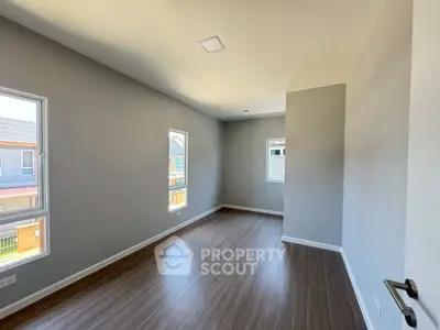 Spacious empty room with large windows and wooden flooring in modern home