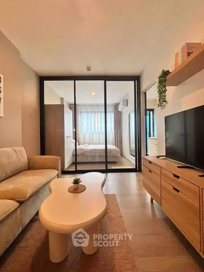 Modern living room with cozy sofa, stylish coffee table, and view into a bright bedroom through glass doors.