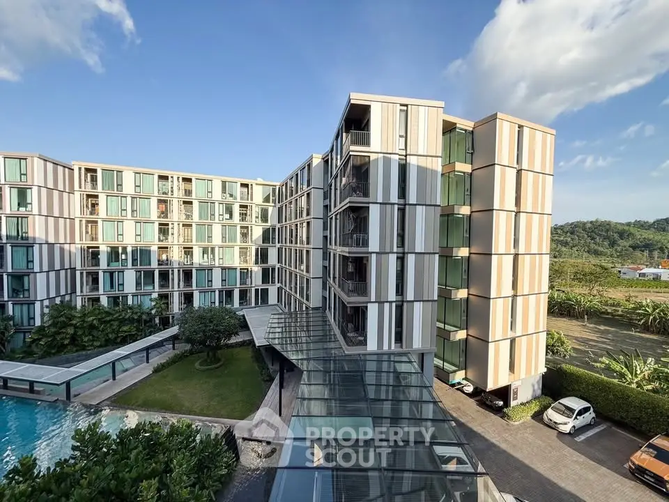 Modern apartment building with pool and lush greenery under blue sky