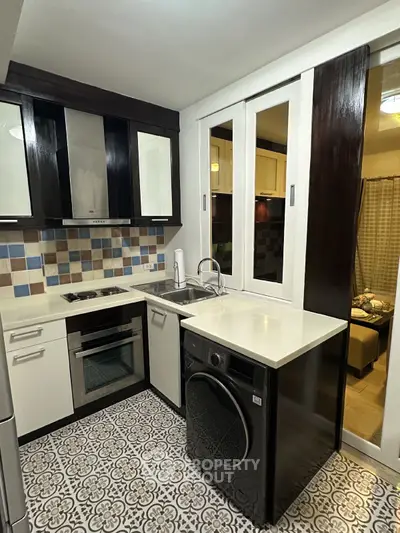 Modern kitchen with sleek appliances and stylish tile flooring, featuring a compact open layout.