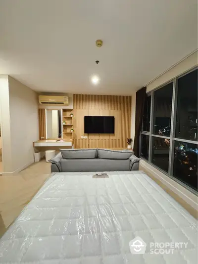 Modern bedroom with large windows and city view, featuring stylish decor and comfortable furnishings.