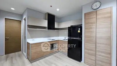 Modern kitchen with sleek cabinetry and black fridge in stylish apartment