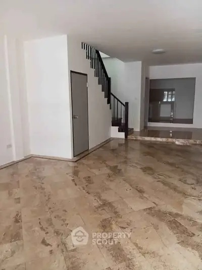 Spacious open-plan living area with elegant staircase and marble flooring