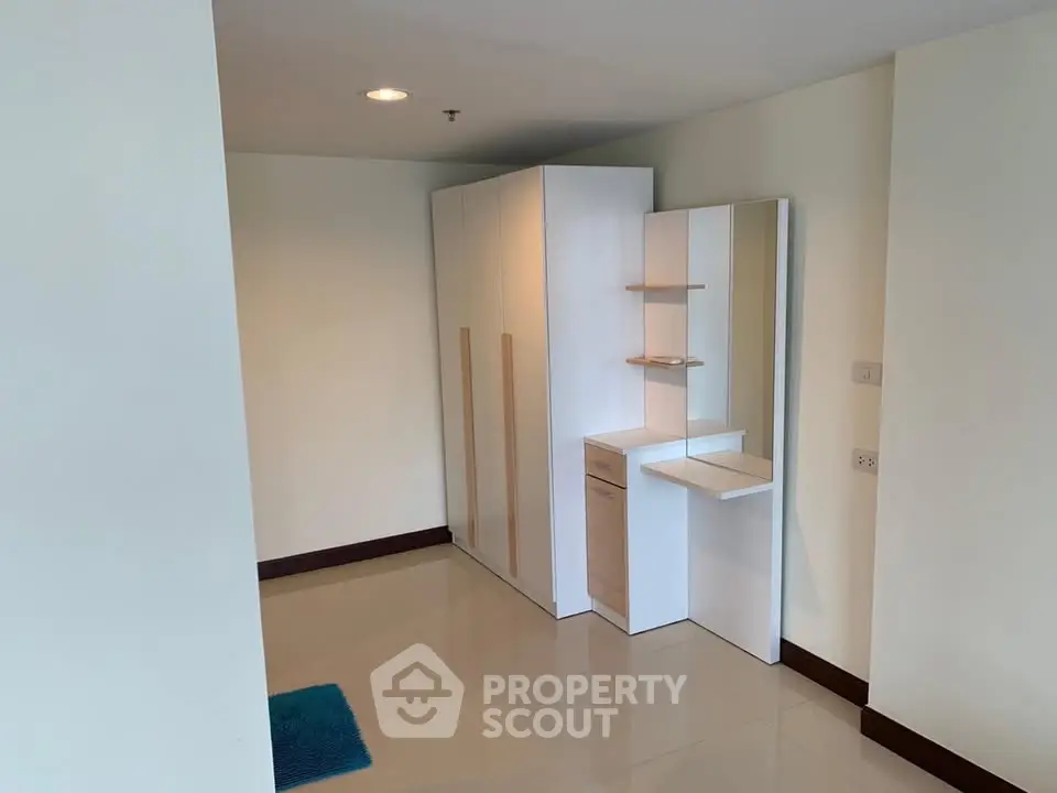 Modern minimalist bedroom with sleek wardrobe and vanity in a bright interior.