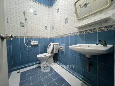 Charming blue-tiled bathroom with modern fixtures and shower, perfect for a cozy home.