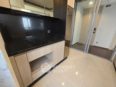Modern kitchen with sleek black countertop and wooden cabinetry in a contemporary apartment.