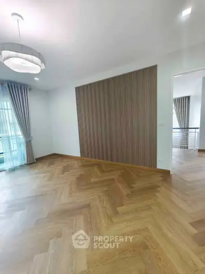 Spacious modern living room with elegant wood flooring and stylish lighting.