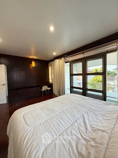 Spacious bedroom with large windows and modern decor, offering a serene and inviting atmosphere.