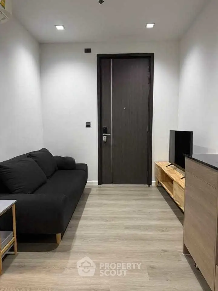 Modern minimalist living room with sleek black sofa and wooden TV stand