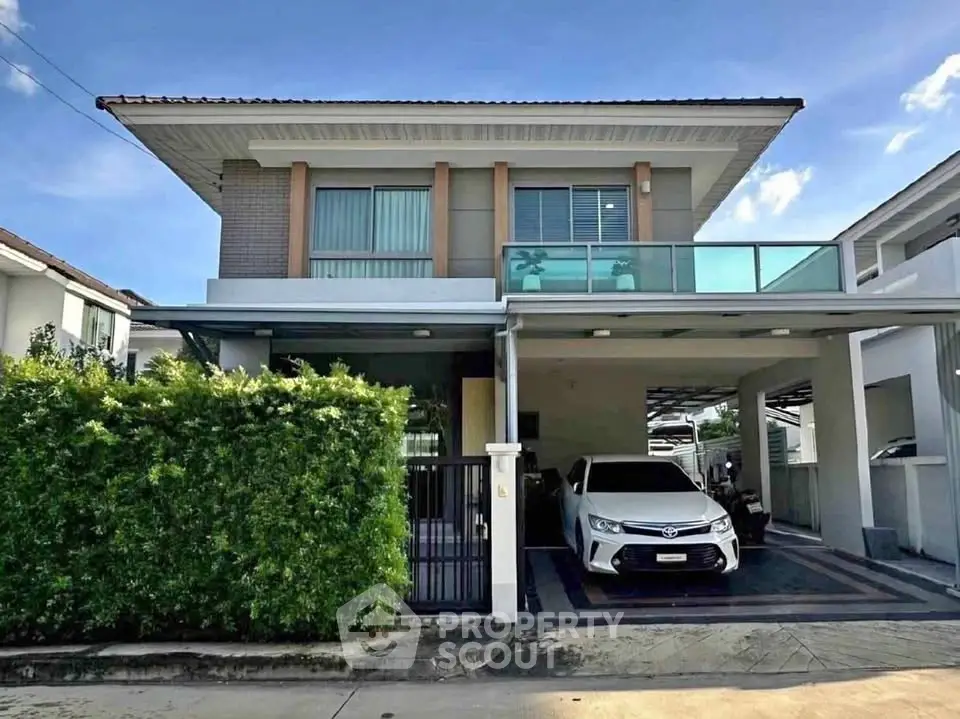 Modern two-story house with carport and lush greenery in a suburban neighborhood.