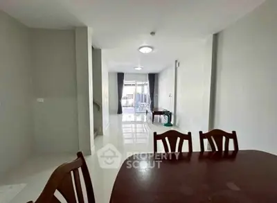 Spacious dining area with elegant wooden table and chairs, leading to a bright living space.
