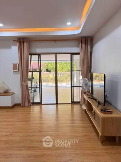 Spacious living room with wooden flooring and large sliding glass doors leading to a balcony.