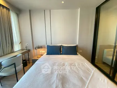 Modern bedroom with stylish decor and natural light, featuring a comfortable bed and work desk.