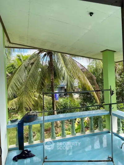 Charming balcony with lush garden view and tropical palm trees, perfect for relaxation.