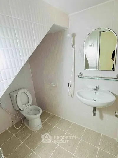 Modern bathroom with sloped ceiling and minimalist fixtures.