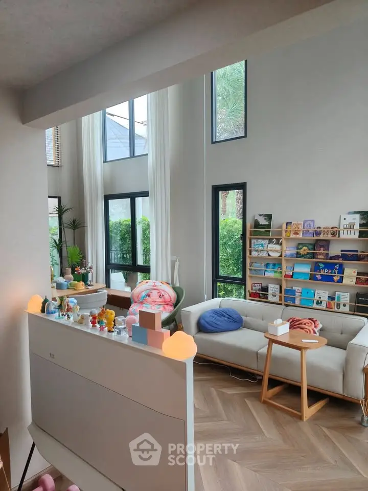 Spacious living room with high ceilings and large windows, featuring modern decor and abundant natural light.