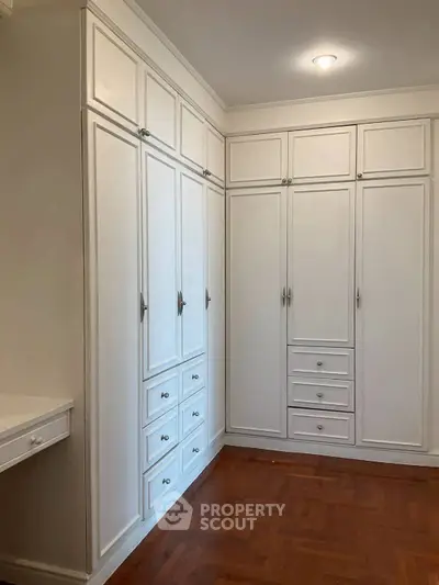 Spacious white built-in wardrobes in a modern bedroom with wooden flooring.