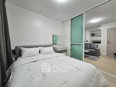 Modern bedroom with sliding glass door leading to cozy living area, featuring stylish decor and comfortable furnishings.