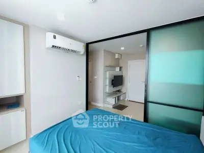 Modern bedroom with sliding glass door and wall-mounted TV in a stylish apartment.