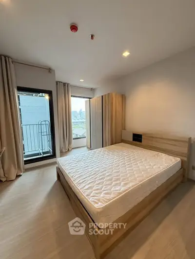 Spacious bedroom with large window and modern wooden furniture in a stylish apartment.