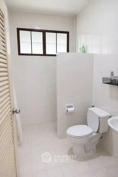 Modern bathroom with white tiles and sleek fixtures in a minimalist design.