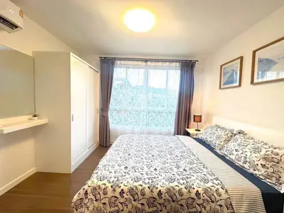 Bright and cozy bedroom with large window and stylish decor, perfect for relaxation.