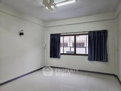 Spacious empty room with large window and blue curtains, ideal for customization.