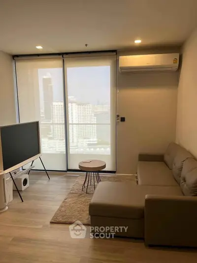 Modern living room with city view, featuring a cozy sofa and sleek TV setup.